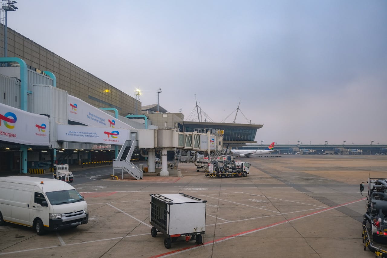 View of an airport apron showcasing vehicles, tarmac, and gates on a cloudy day.
